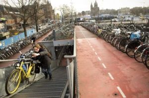 A man parks her bicycle at a bicycle parking lot near a station in the Netherlands
